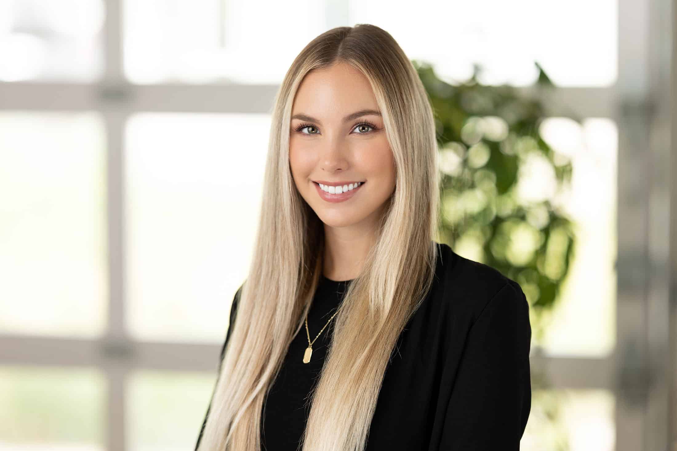 A woman with long blonde hair smiling in an office, showcasing different lighting styles.