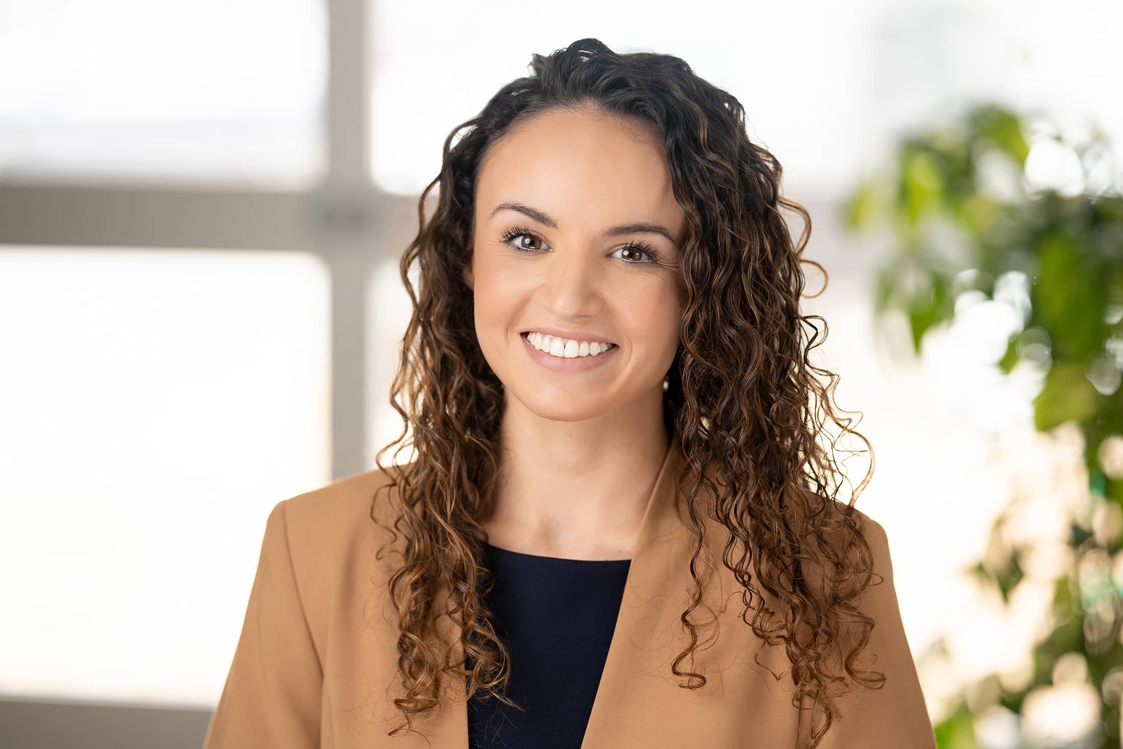 a smiling woman in a tan blazer.