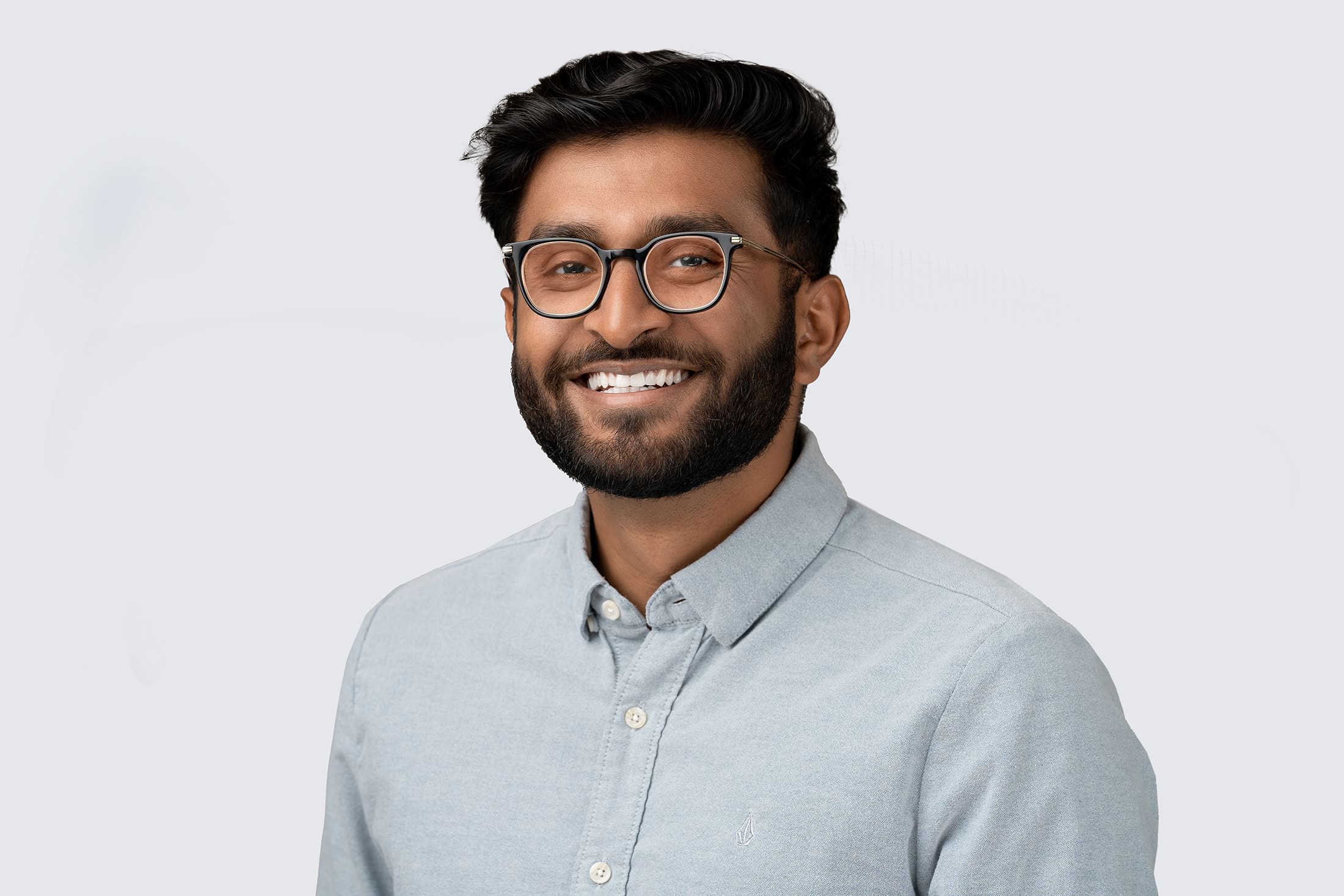 a man with glasses and a beard smiling.