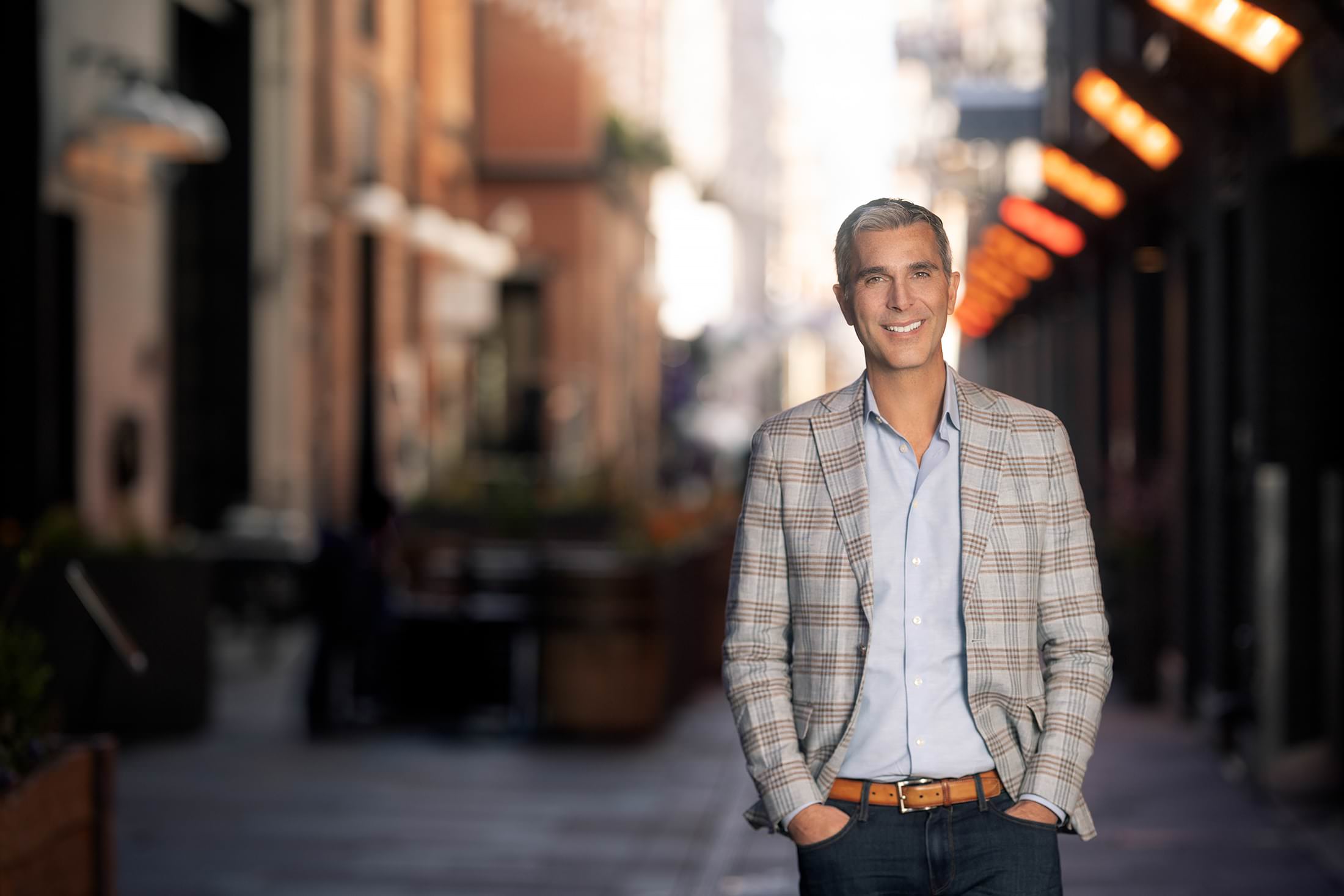 a man in a blazer standing on a city street, showcasing how headshots help with growth.