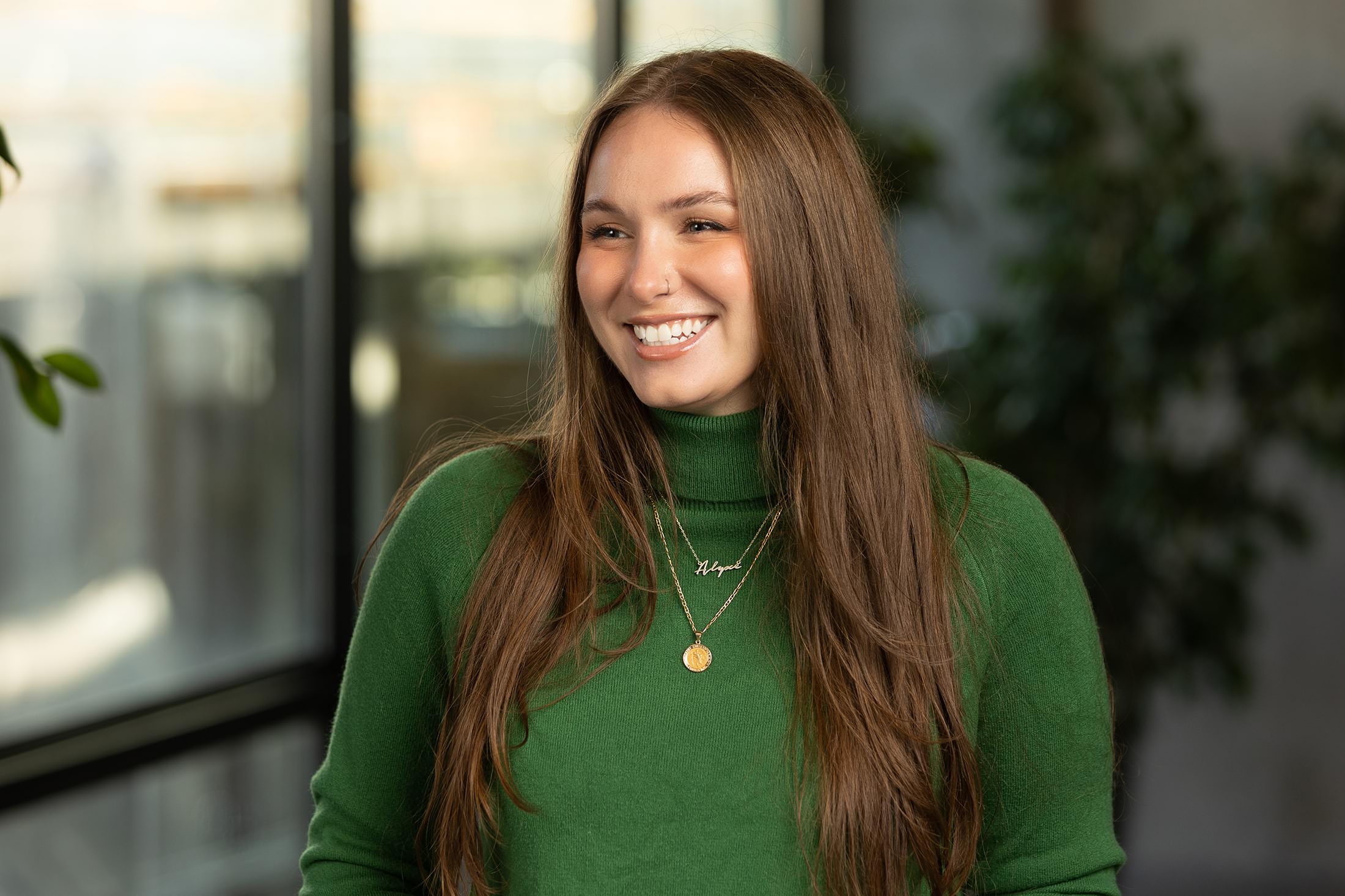 a smiling woman in a green turtleneck sweater.