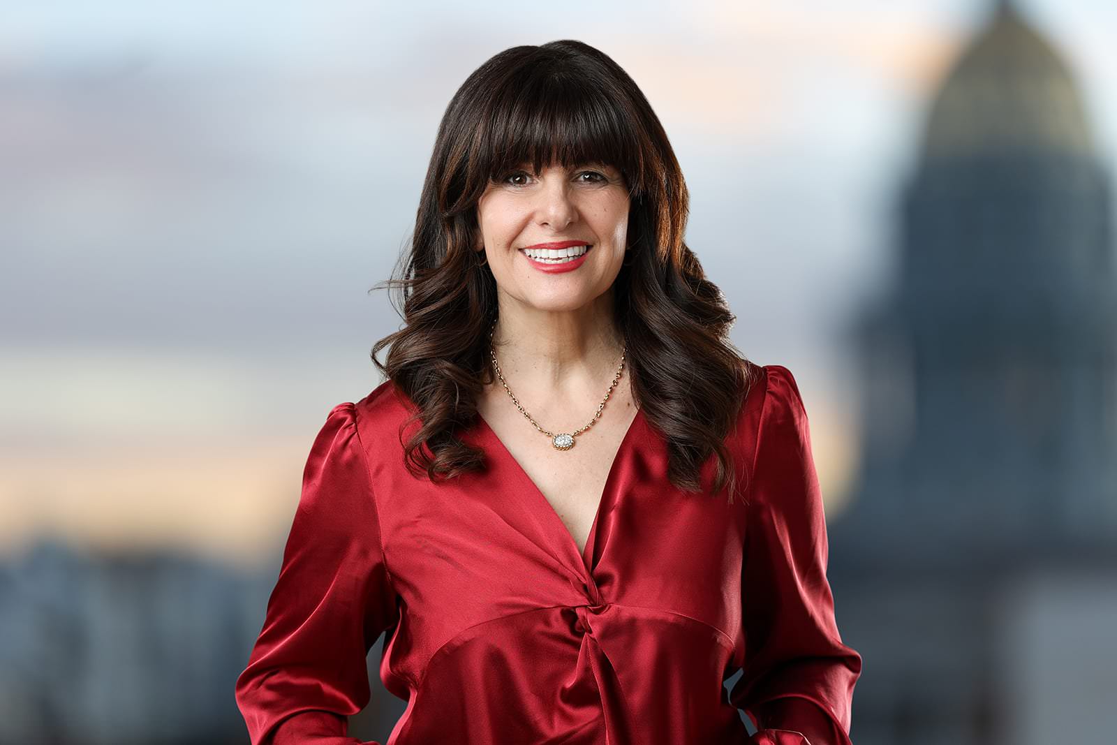 a woman in a red shirt standing in front of a city.