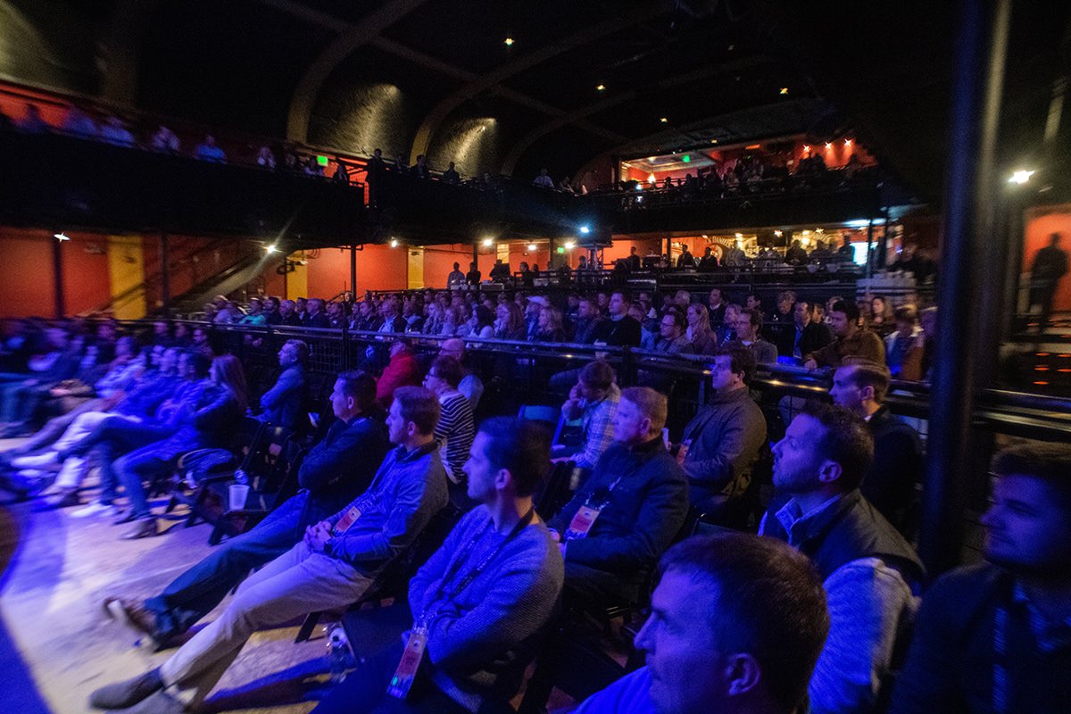 a crowd of people in an auditorium watching a performance.