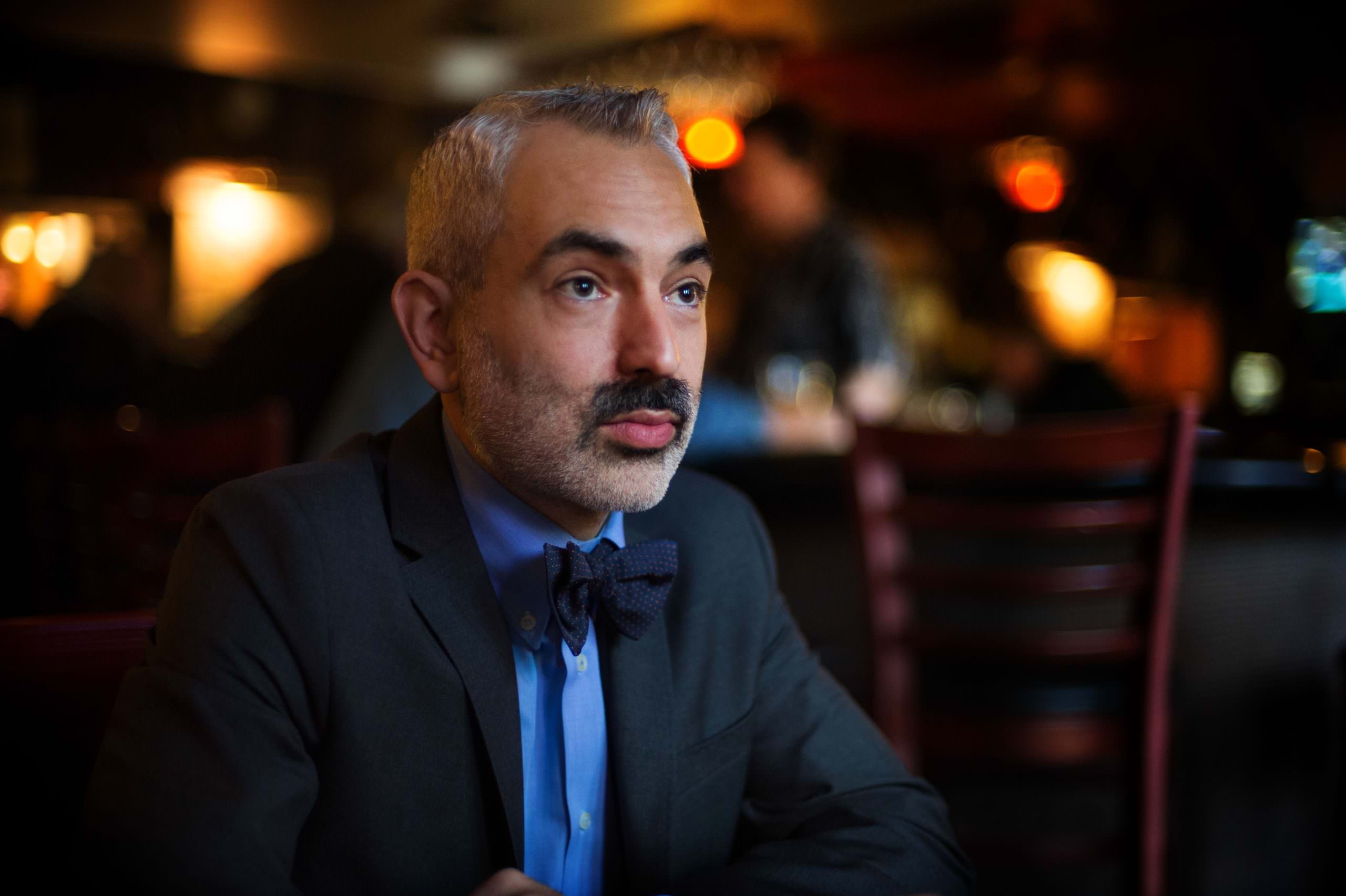a man in a suit sitting at a bar.