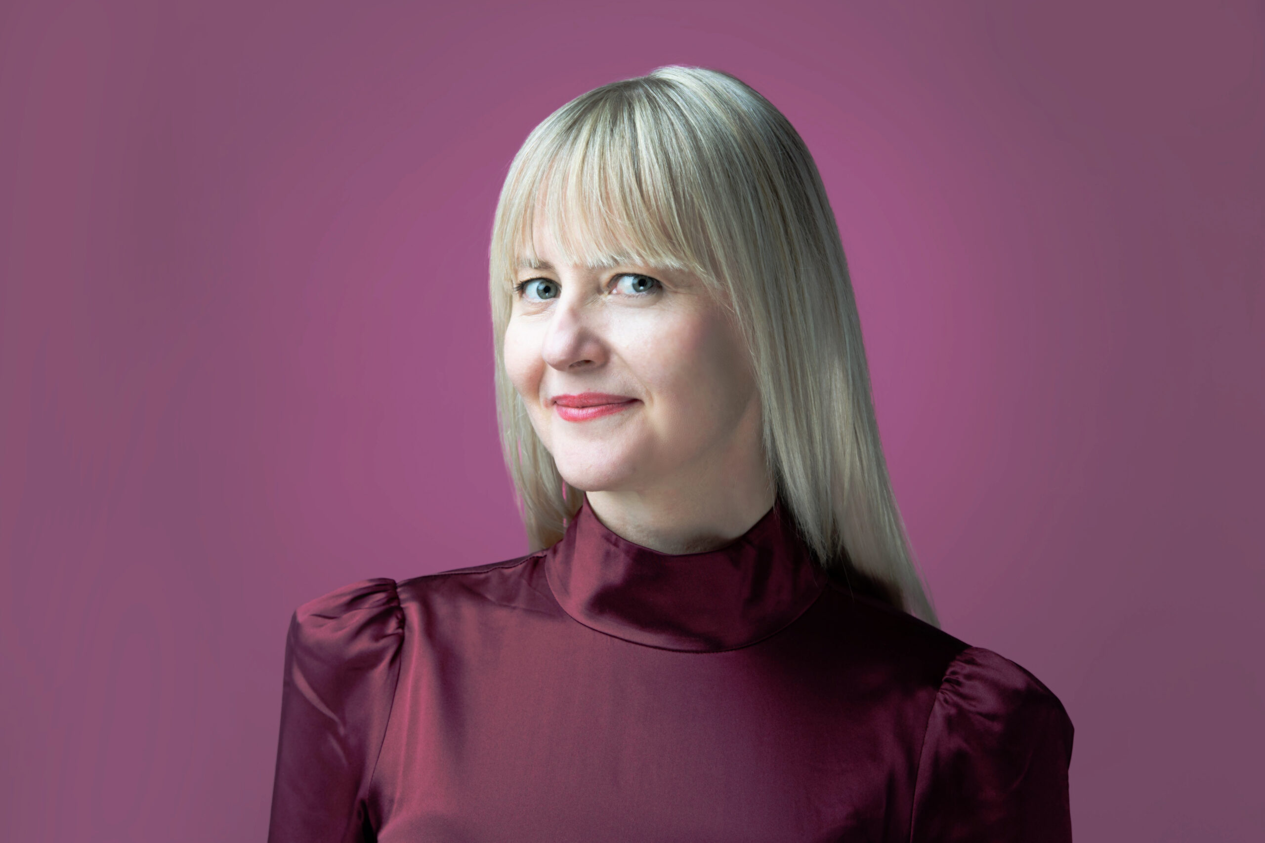 A woman in a maroon top posing for a creative headshot photo.