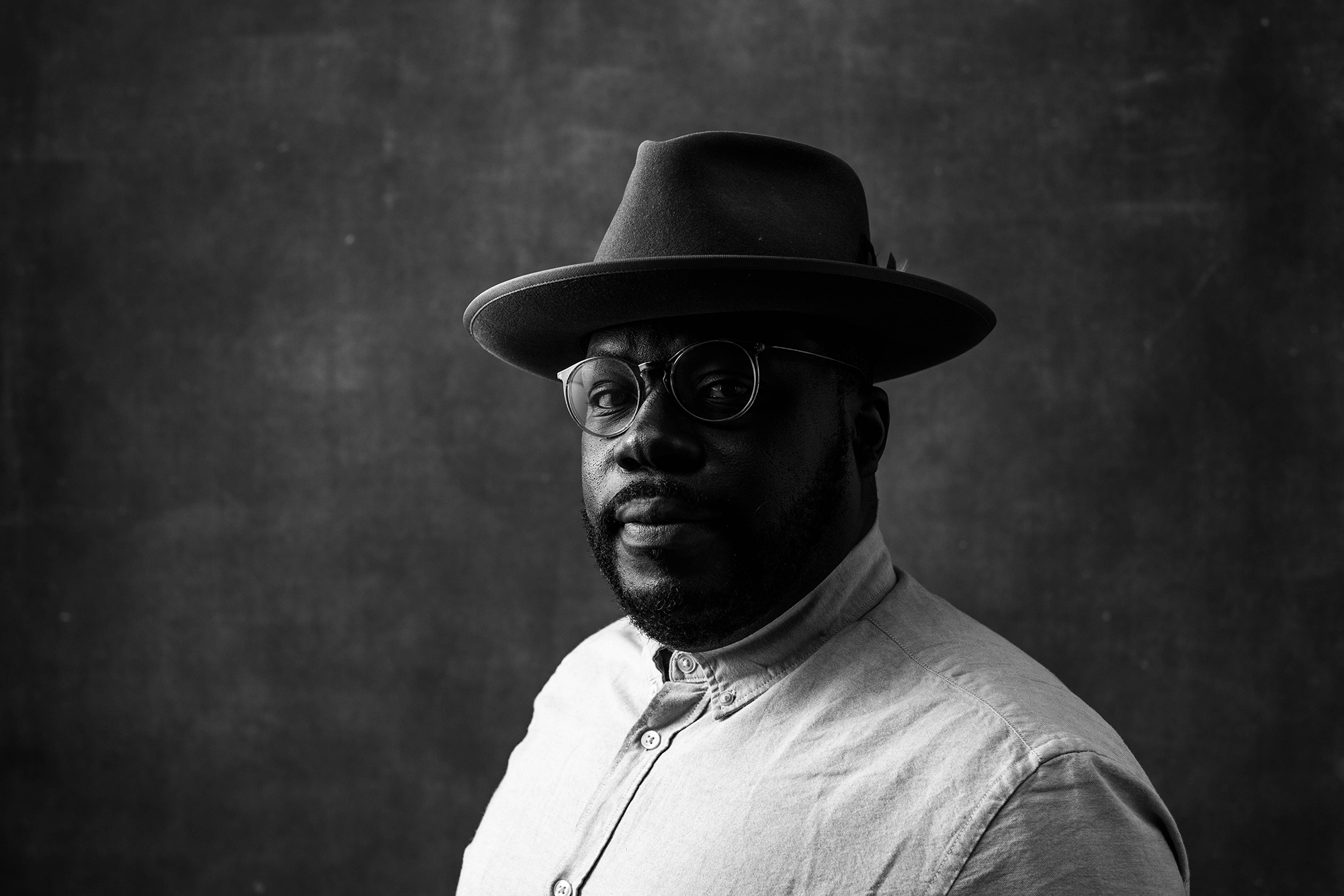 A creative headshot capturing a man in a hat in black and white.