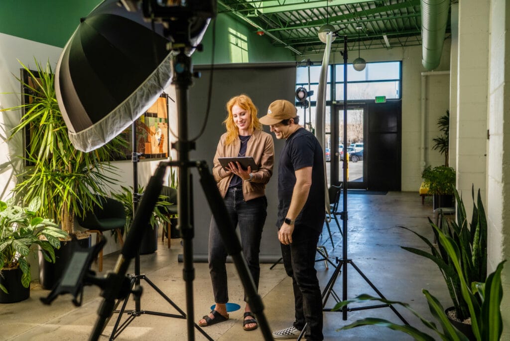 two people standing in front of a camera in an office.