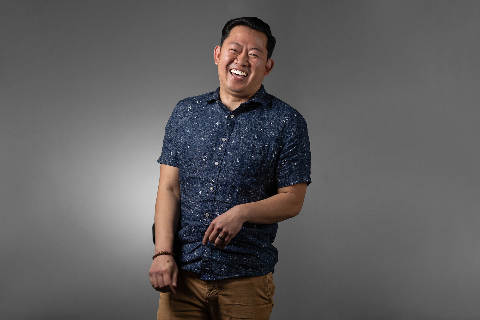         Description: A smiling man wearing a blue shirt and tan pants for corporate headshots.