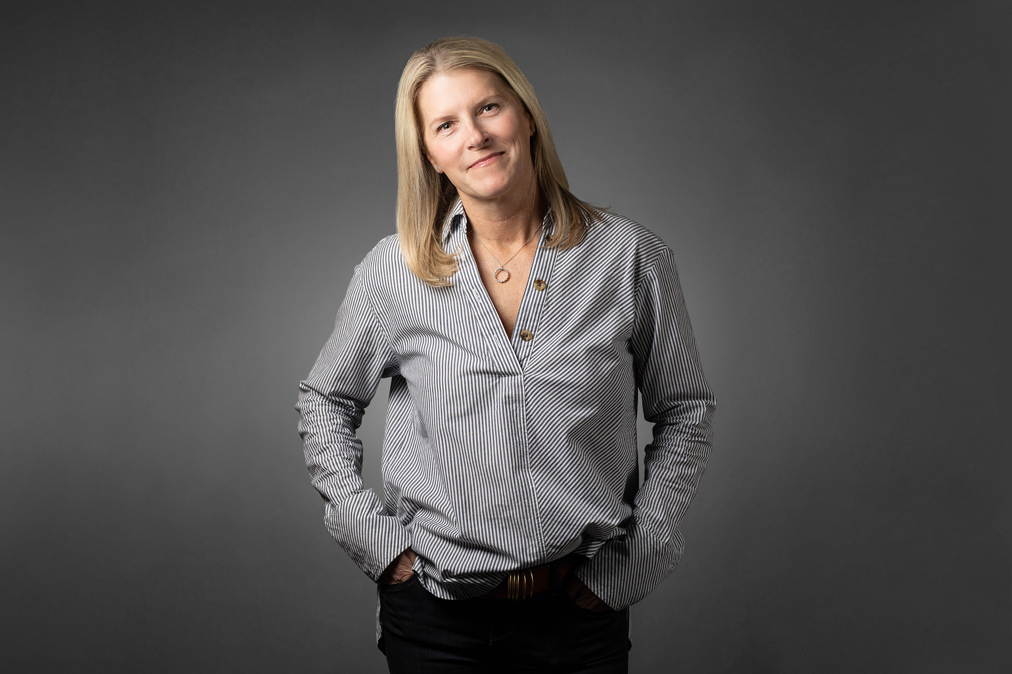 A woman in a gray shirt posing for a Corporate Headshots photo.