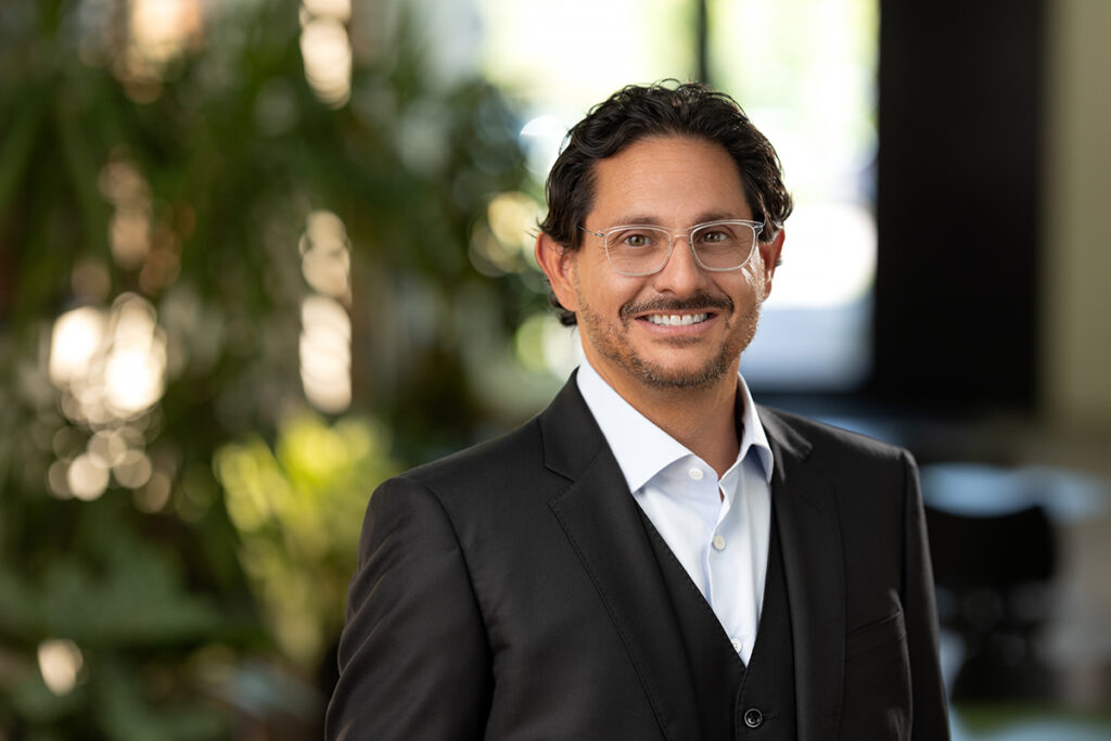 Confident professional posing for a headshot with a blurred background.