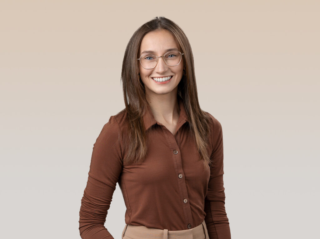 A young woman in a brown shirt and tan skirt posing for individual headshots.