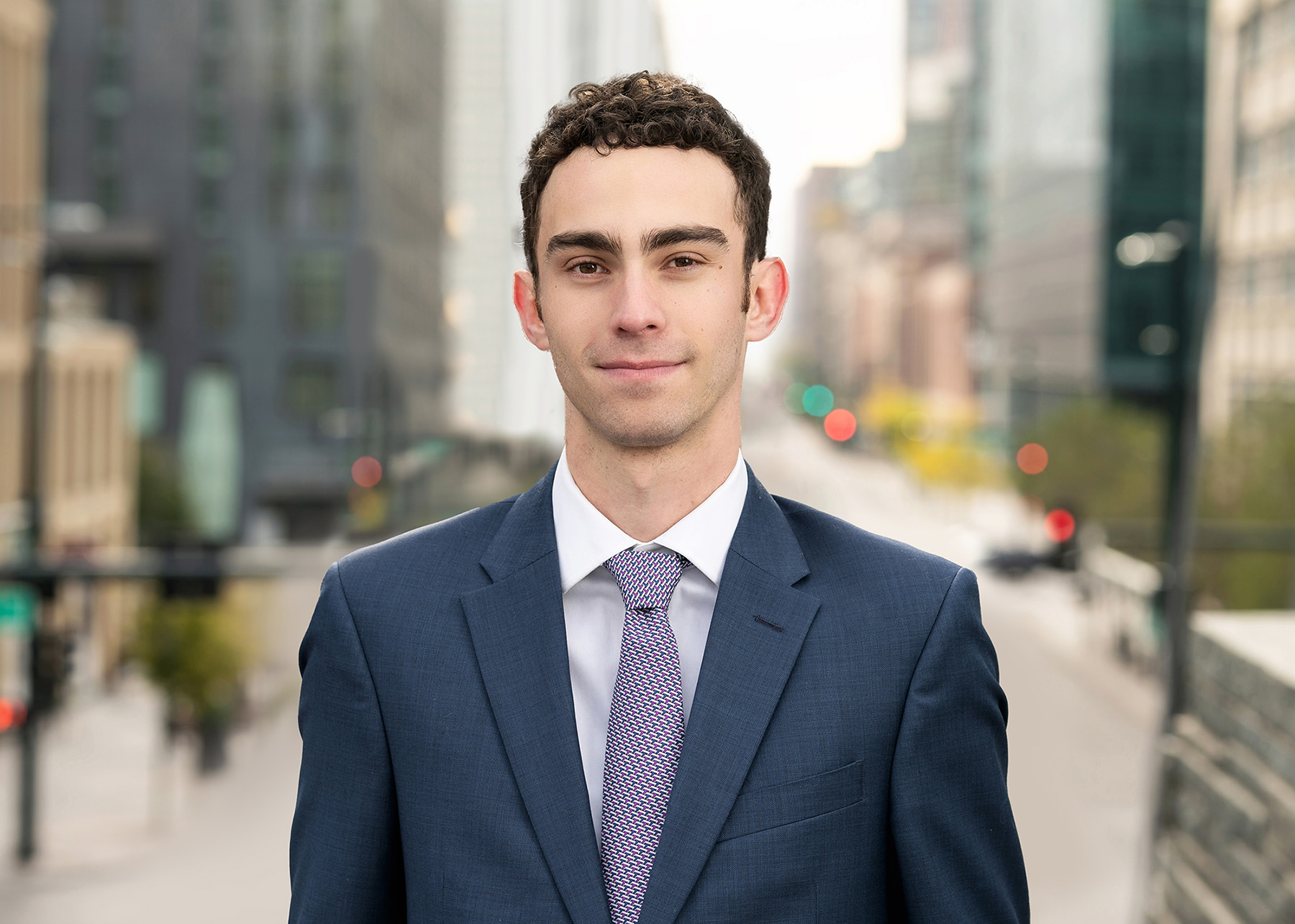 Young man in a business suit standing on an urban Denver street for his headshots.