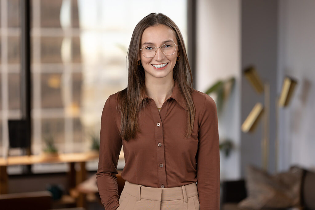 Professional woman smiling in Denver office environment, showcasing her headshot.