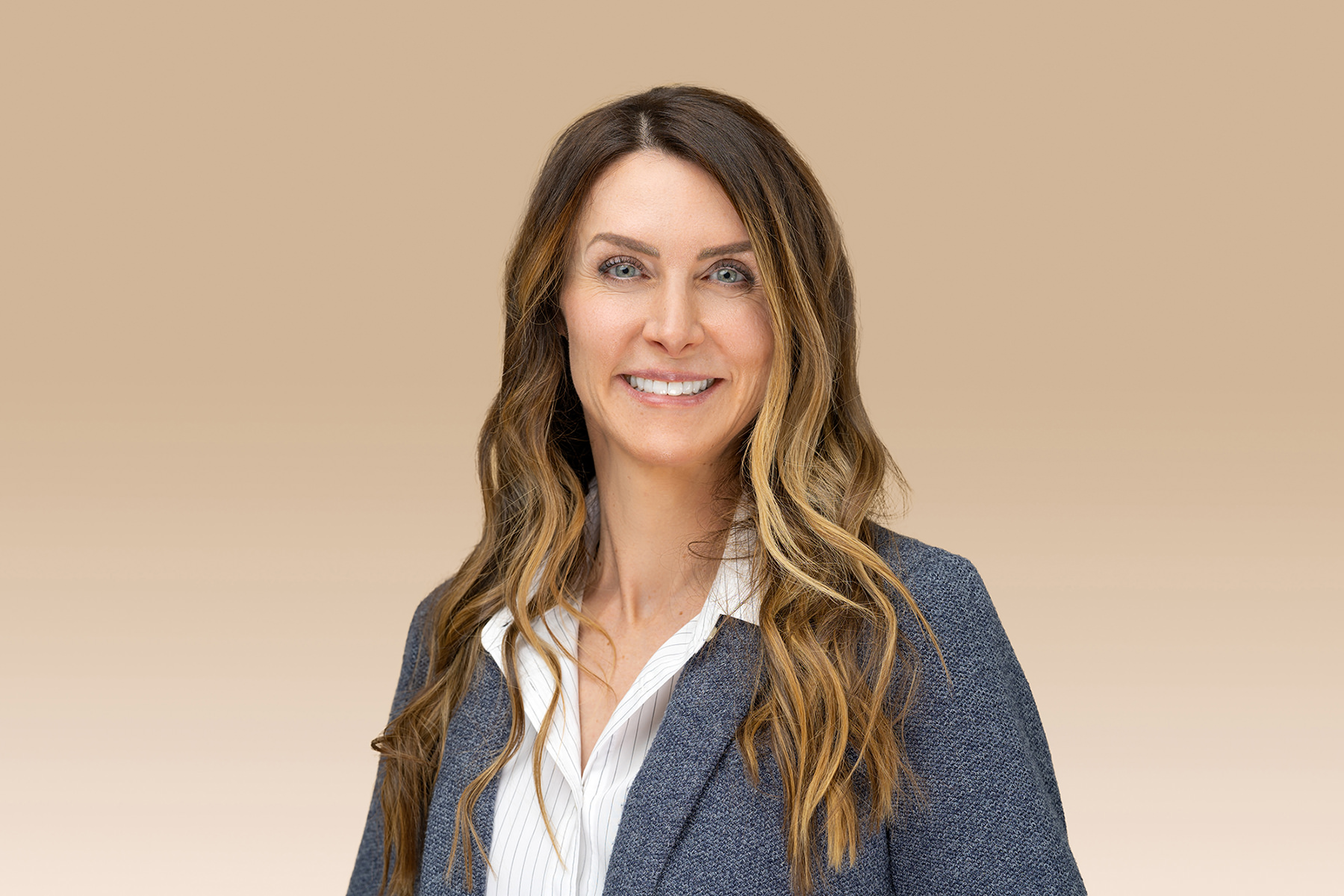 Professional woman in business attire, posing for Denver headshots, smiling against a neutral background.
