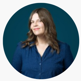 Woman with long brown hair wearing a blue button-up shirt, standing in front of a dark teal background—an example of modern headshots for professionals.
