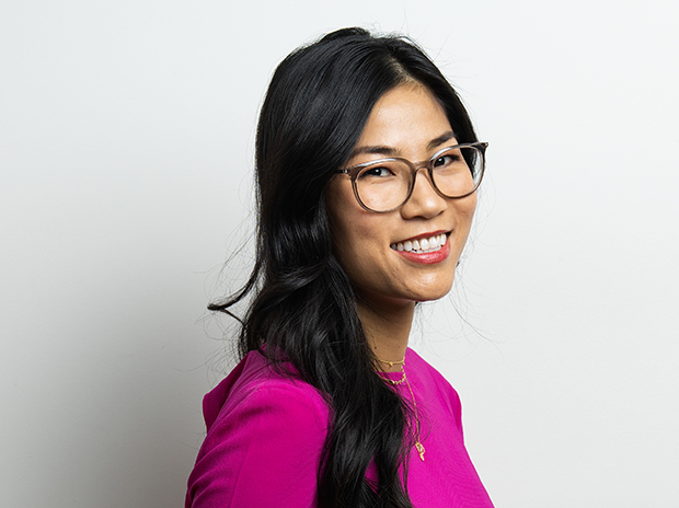 Person in glasses smiling and wearing a bright pink top.