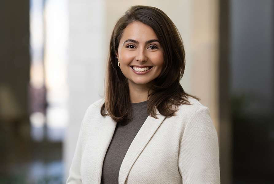 Smiling woman in a white blazer in an office setting.